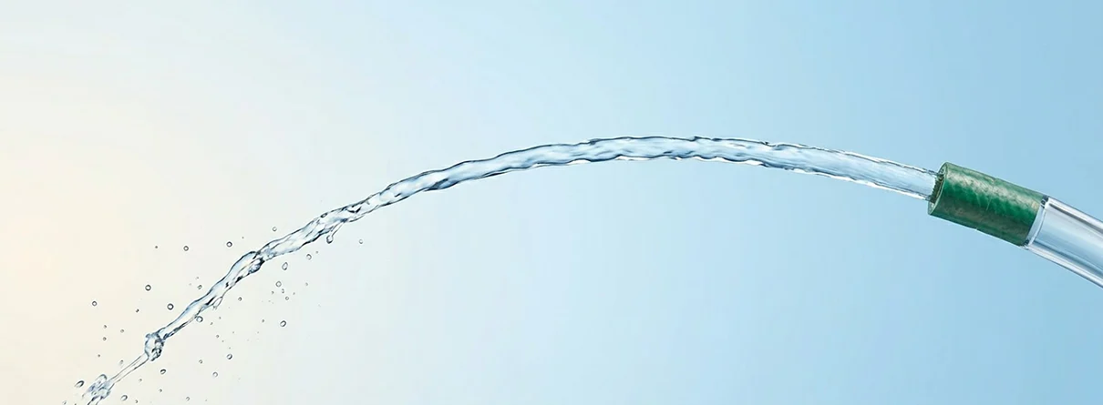 OP Header Meatusrekonstruktion Dieses Symbolbild für eine erfolgreiche Meatusrekonstruktion zeigt einen Gartenschlauch, an dessen Ende ein Stück neuen Schlauches eingesetzt wurde und der einen starken Wasserstrahl abgibt. CUROS urologisches Zentrum